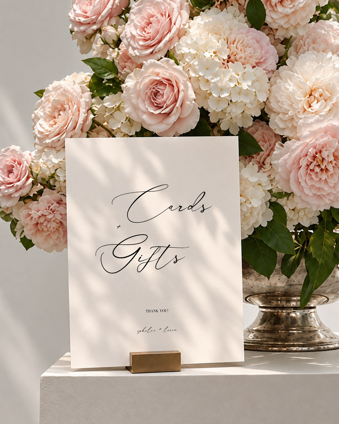 Aria acrylic wedding cards and gifts sign in a gold holder beside pink roses and white hydrangeas
