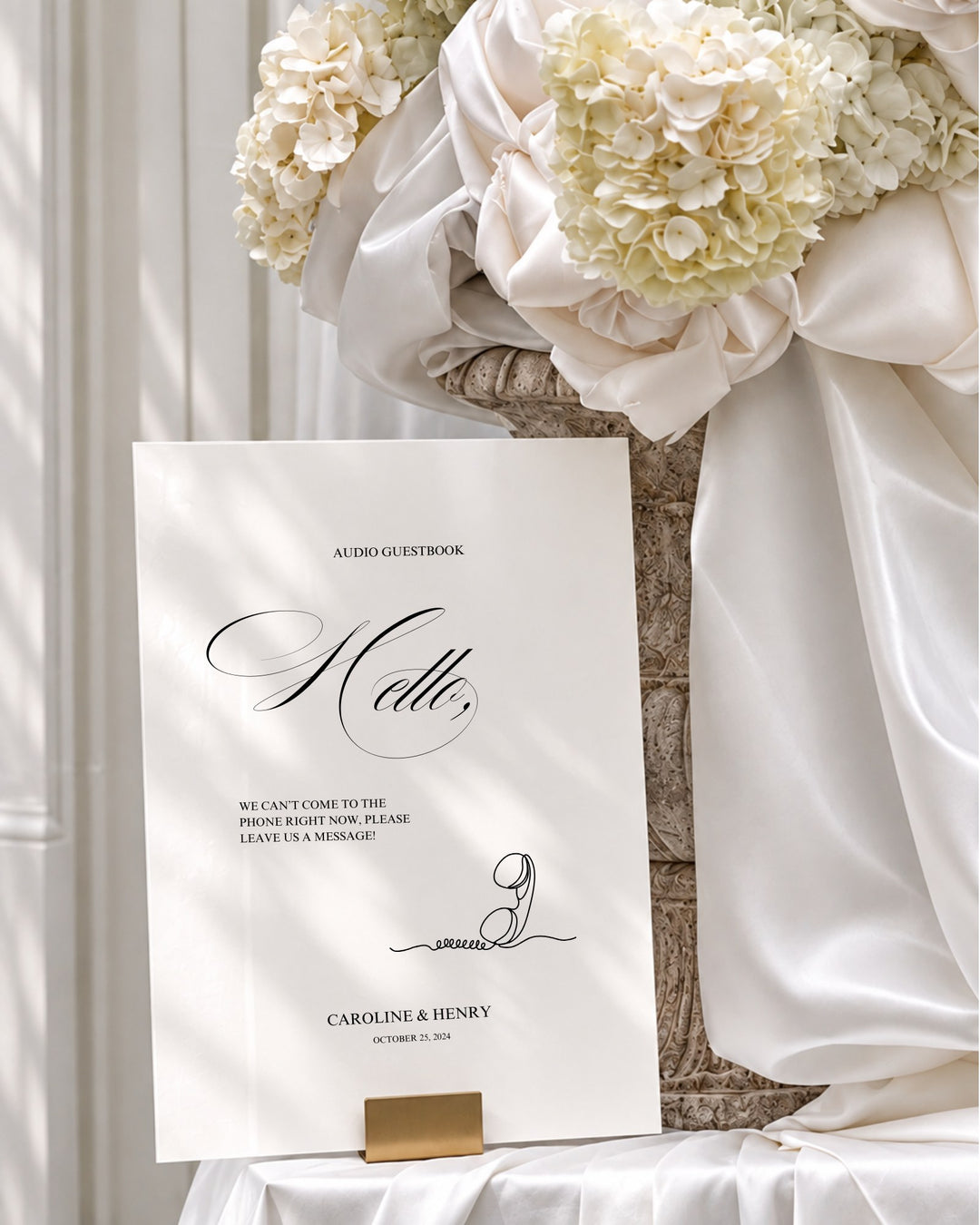 Florence acrylic wedding guestbook sign in a gold holder beside draped ivory silk and hydrangeas
