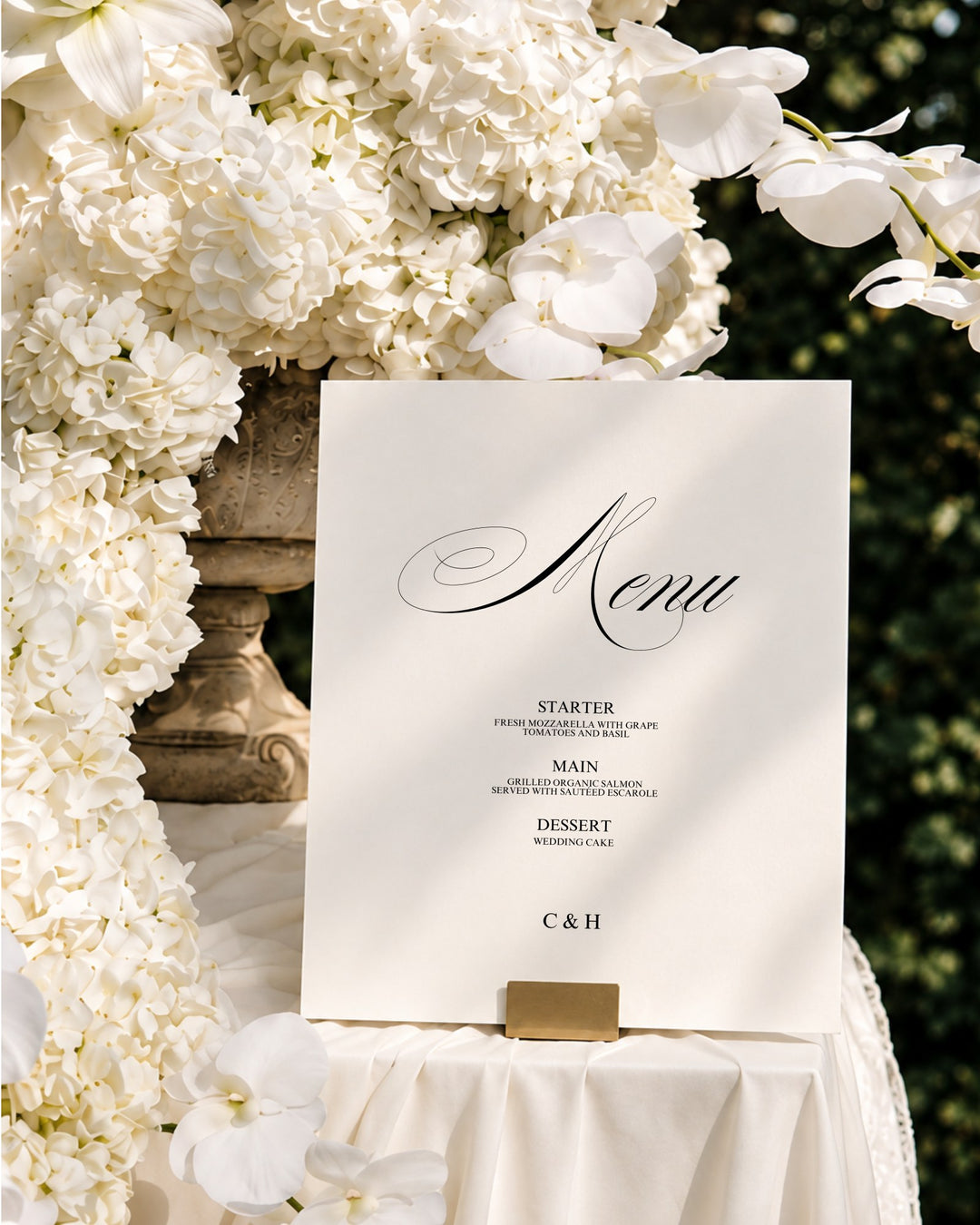 Florence acrylic wedding menu sign in a gold holder among white orchids and hydrangeas