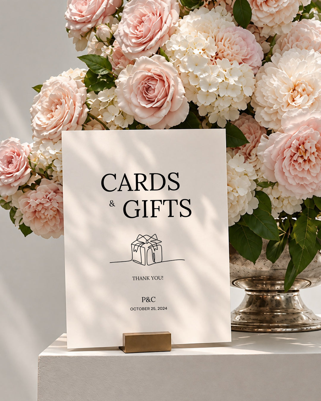 Moda acrylic wedding cards and gifts sign in a gold holder beside pink roses and white hydrangeas
