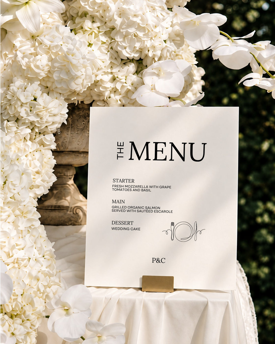Moda acrylic wedding menu sign in a gold holder among white orchids and hydrangeas