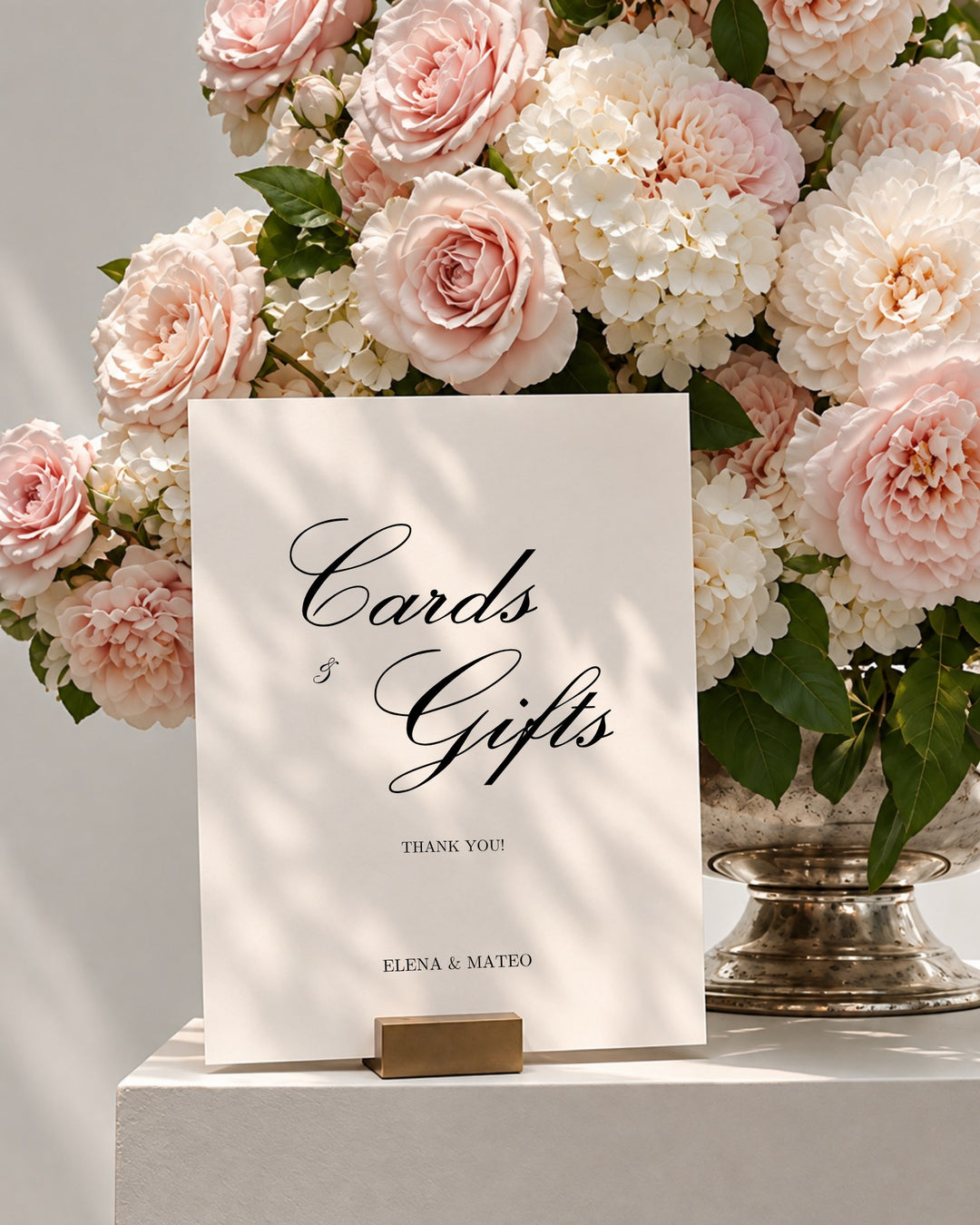 Reina acrylic wedding cards and gifts sign in a gold holder beside pink roses and white hydrangeas